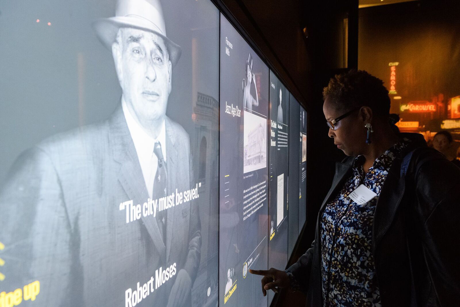 Photograph of an educator examining stories of New Yorkers from the 20th century in the World City gallery.